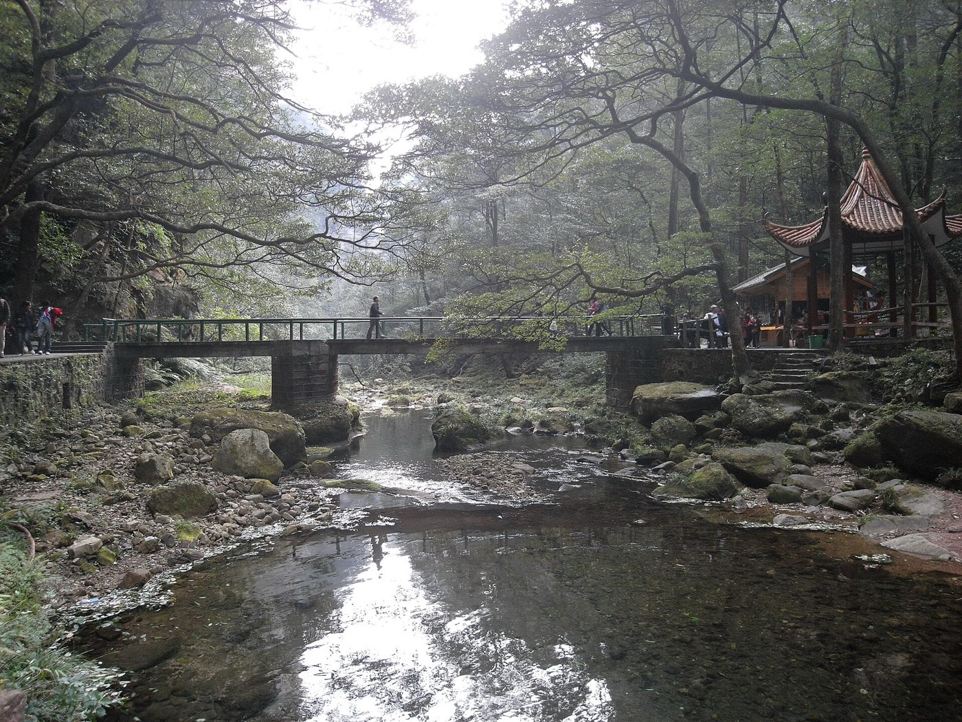 Golden Whip Stream flowing under a stone footbridge beside a Chinese pavilion in Zhangjiajie National Forest Park